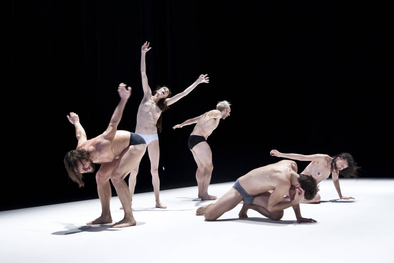 Dancers fold over their bodies, mouths open